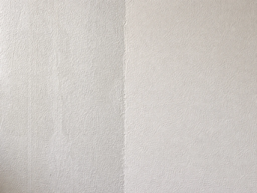 Close-up comparison of two wall paint sections: uneven streaks on one, smooth even coverage on the other.