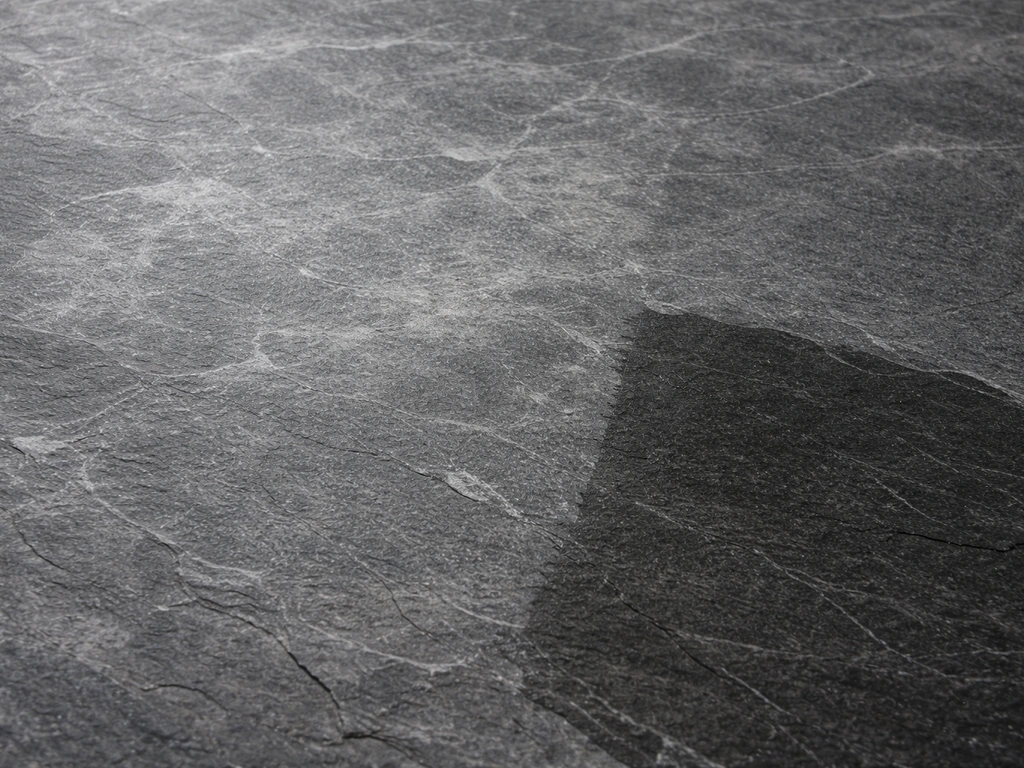 Close-up of blotchy white sealer haze on slate beside a freshly wiped, clearer patch.