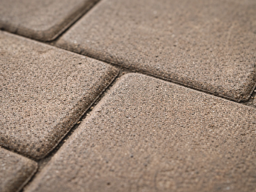 Close-up of evenly dull, brownish patio pavers showing embedded grime in the surface pores.